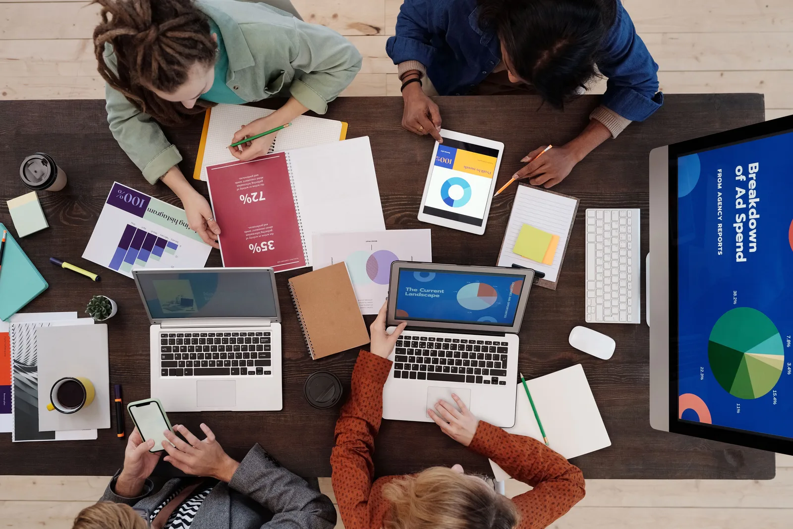 A diverse team collaborating on digital marketing strategies at a desk, using laptops and tablets. Which campaign operations mistakes only surface after launch?