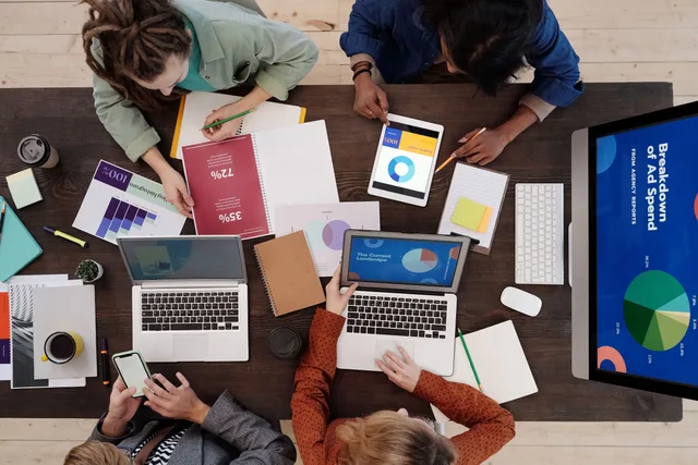 A diverse team collaborating on digital marketing strategies at a desk, using laptops and tablets. Which campaign operations mistakes only surface after launch?