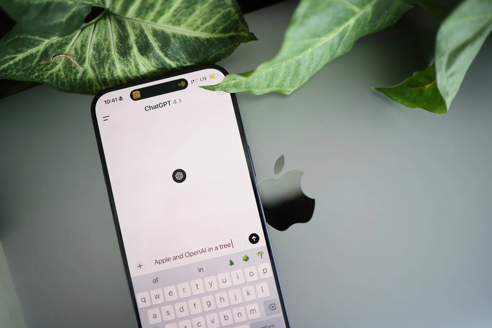 A smartphone shows a ChatGPT interface placed on an Apple laptop in a leafy environment. CRM strategy trends: agents, unified context and growing resilience