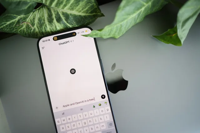 A smartphone shows a ChatGPT interface placed on an Apple laptop in a leafy environment. CRM strategy trends: agents, unified context and growing resilience