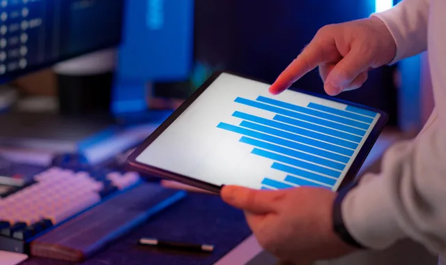Business professional analyzing bar chart on tablet in office setting, highlighting data insights. Customer data platforms features: a buyer's checklist