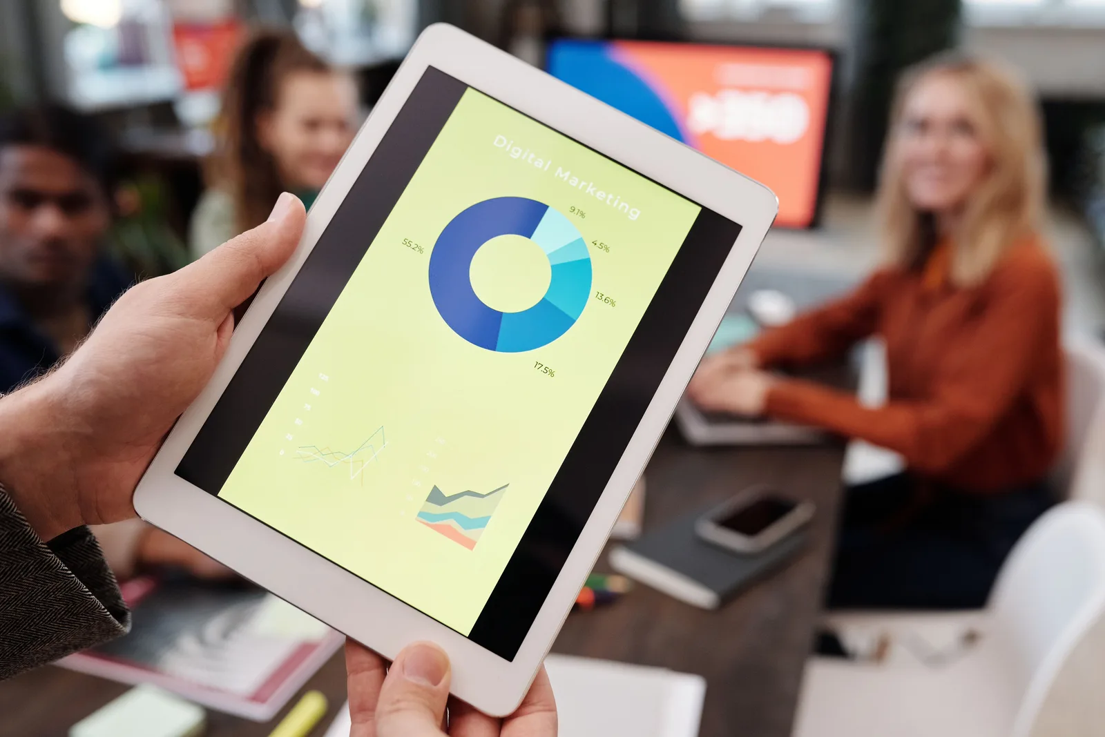 Business team reviewing digital marketing statistics on a tablet during an indoor meeting. Marketing resource management examples, taken apart